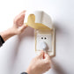Beige childproof outlet cover with flap open, corded plug secured inside