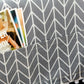 Folded microwave dust cover fabric in dark gray with white arrow pattern, pom trim edge