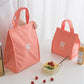 Orange insulated lunch bag tote with open interior and carrying handle for snacks.