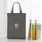 Grey insulated lunch bag tote holding bottles and food, portable picnic storage.