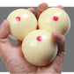 Set of three cream training billiard balls with red dots, held in hands