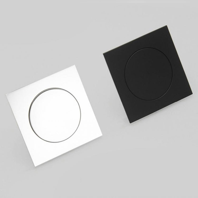 Foot-operated floor drain cover with circular button, black and white square plates