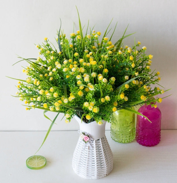 Yellow simulation flower bouquet in a white textured vase with decorative lid detail
