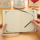 Opened vintage pocket notebook with lined pages and black ribbon bookmark.