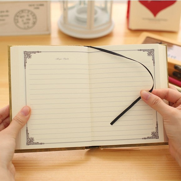 Opened vintage pocket notebook with lined pages and black ribbon bookmark.