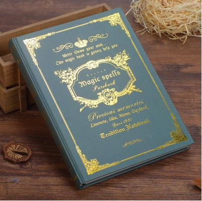 Green vintage pocket notebook with ornate gold spell design on the cover.