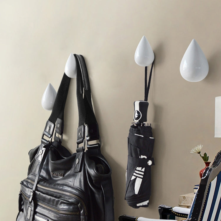 White resin water droplet wall hooks with black straps, shown with hanging bags