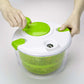 Hands using a green salad spinner lid on a white top with green mesh basket