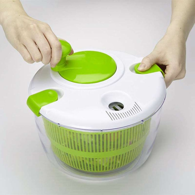 Hands using a green salad spinner lid on a white top with green mesh basket