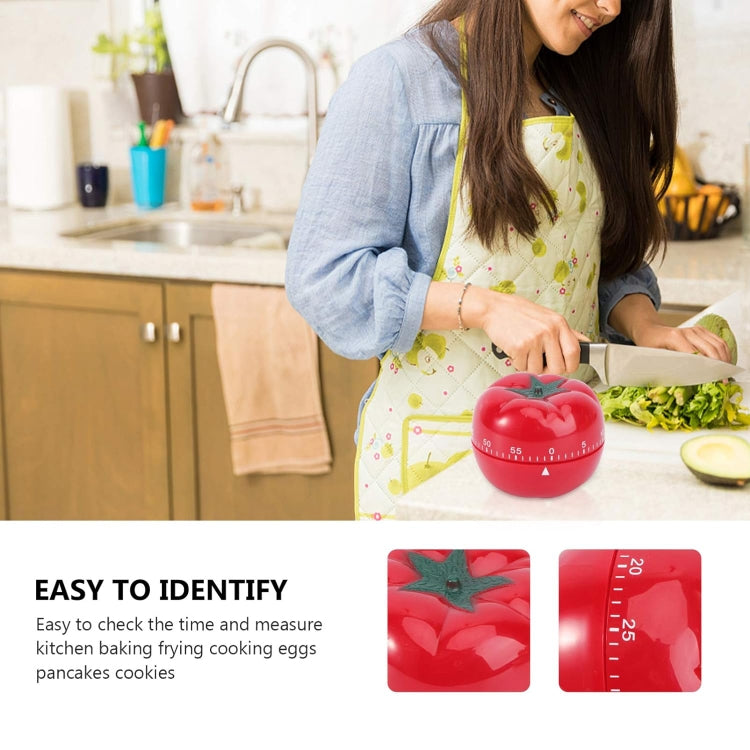 Red tomato-shaped mechanical kitchen timer with green stem on countertop