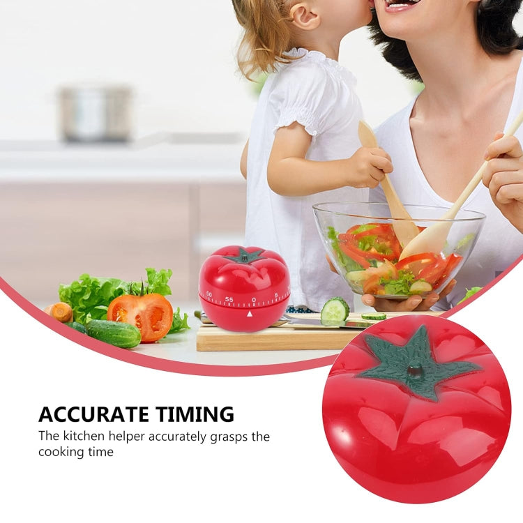 Red tomato-shaped mechanical timer with green stem, shown during food prep