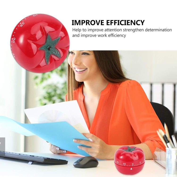 Red tomato-shaped mechanical timer with green stem on desk