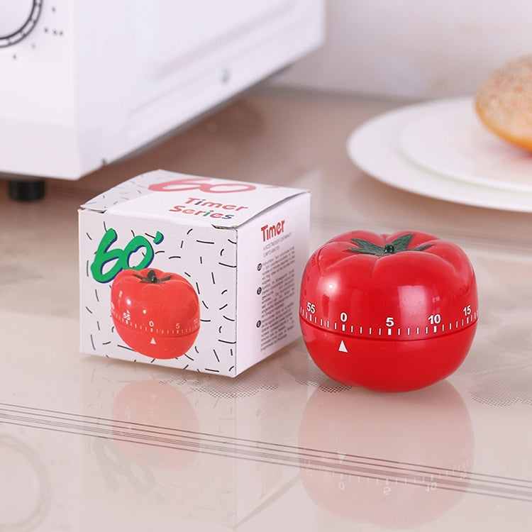 Red tomato-shaped mechanical timer with green stem next to product box