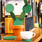 Cactus coaster in use on a table: white cup on cork pad with green felt cactus in orange pot.
