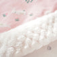 Close-up of baby blanket fabric: pink patterned top with soft white plush underside
