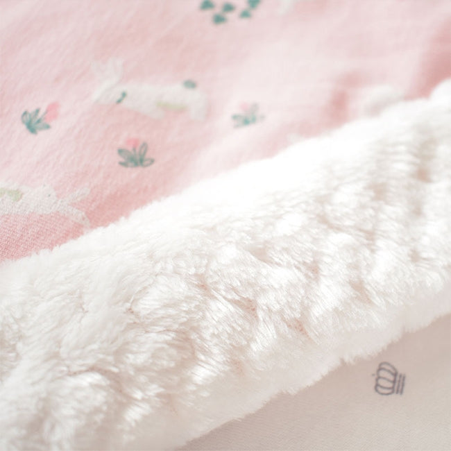 Close-up of baby blanket fabric: pink patterned top with soft white plush underside