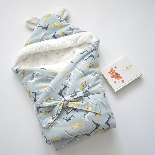 Light blue baby holding blanket with dinosaur print, white fleece trim, and tied bow