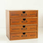 Wooden storage cabinet with four front drawers and arched pull handles, no items visible.