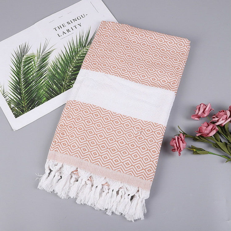 Folded peach and white zigzag cotton bath towel with white center band and tassels