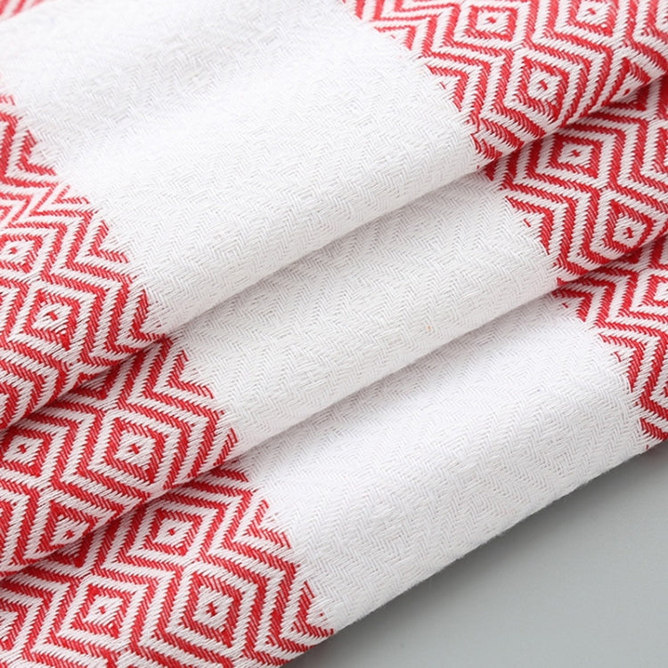 Folded white cotton towel with red zigzag border and thick woven texture