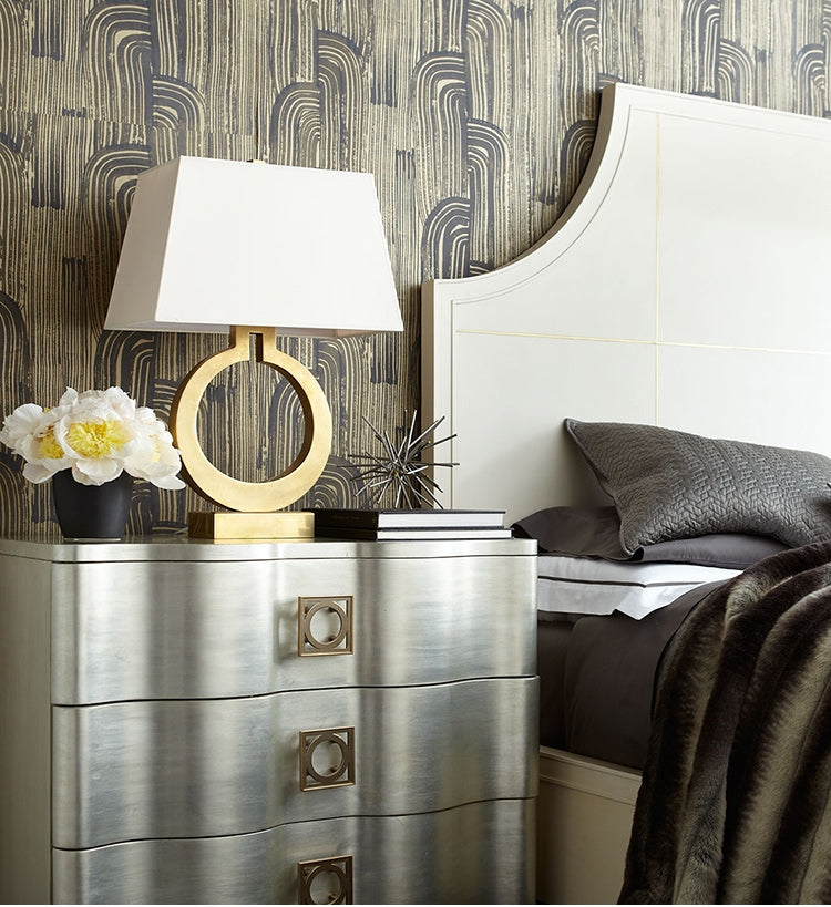 Retro bedside lamp with oval ring base on dark dresser, beige shade