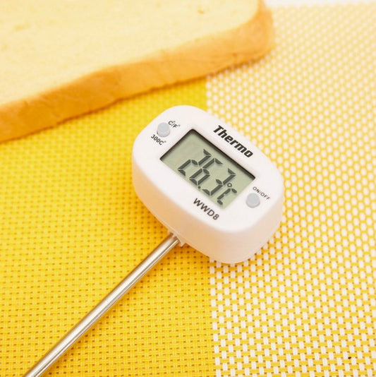 Digital food thermometer with LCD display and metal probe on yellow surface