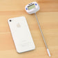 Food thermometer with long metal probe and LCD unit on light wooden table