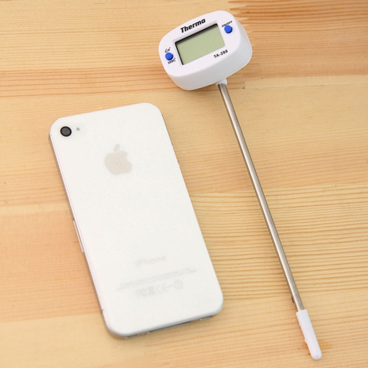 Food thermometer with long metal probe and LCD unit on light wooden table