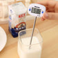 Hand holding digital food thermometer with LCD reading and metal probe in container