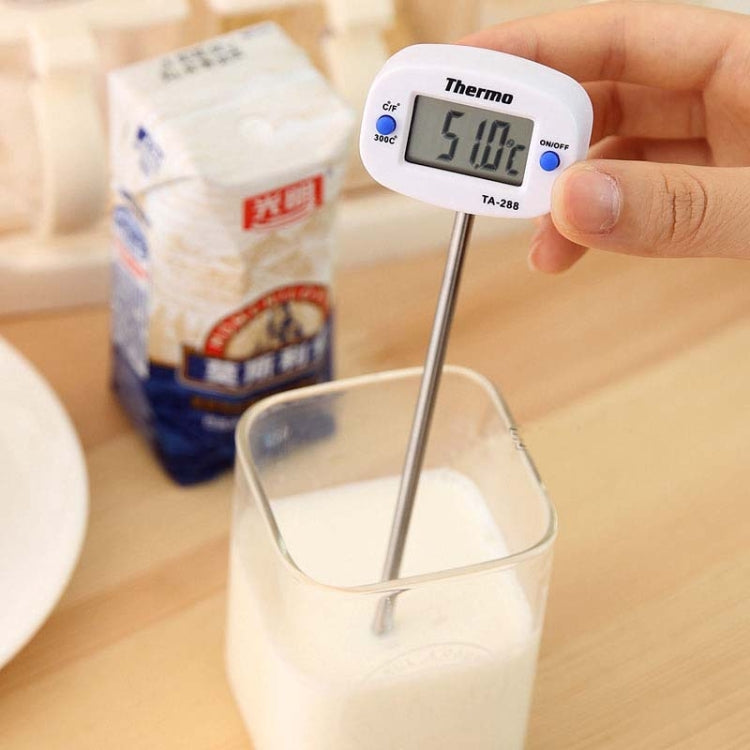 Hand holding digital food thermometer with LCD reading and metal probe in container