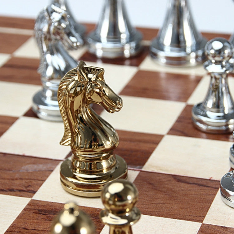 Close-up of a gold knight chess piece on a wooden checkered chessboard