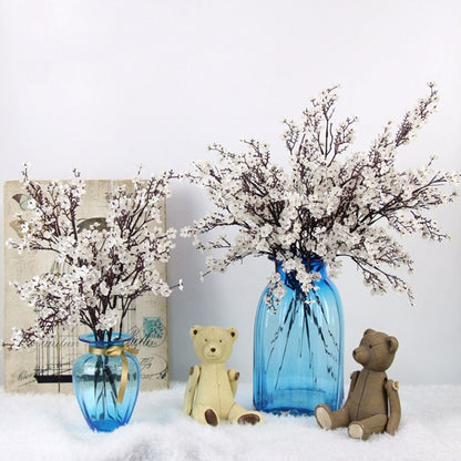 Blue glass vase centerpiece with white artificial blossom branches and teddy bears