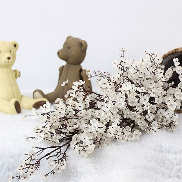 White artificial blossom branches in a dark vase centerpiece with teddy bear decor