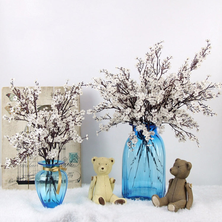 Blue and clear glass vases with white artificial blossom branches and teddy bears