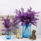 Purple artificial blossom branches in light blue glass vase with teddy bear figurines