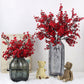 Red artificial blossom branches in clear glass vase with teddy bear figurines