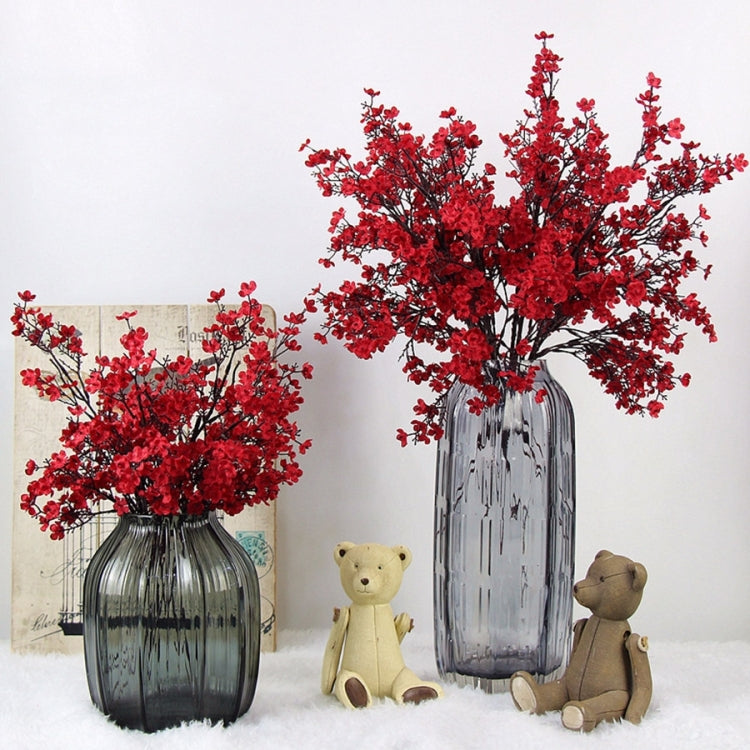 Red artificial blossom branches in clear glass vase with teddy bear figurines