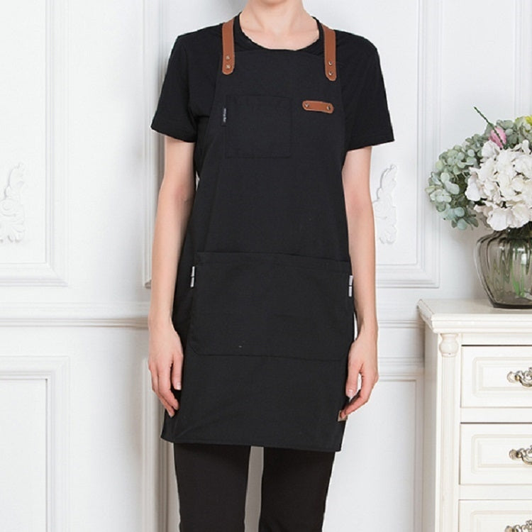 Black canvas apron with brown straps and two front pockets for restaurant work