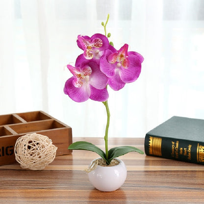 Purple faux Phalaenopsis orchid in white round pot with green leaves
