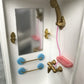 Close-up of white bathroom toy cabinet with gold faucet, pink tub, and blue towel bars