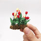 Mini tulip flower model held by hand, red and yellow tulips with green leaves