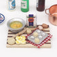 Mini chopping board with toy ingredients, eggs, blister tray, and bread rounds