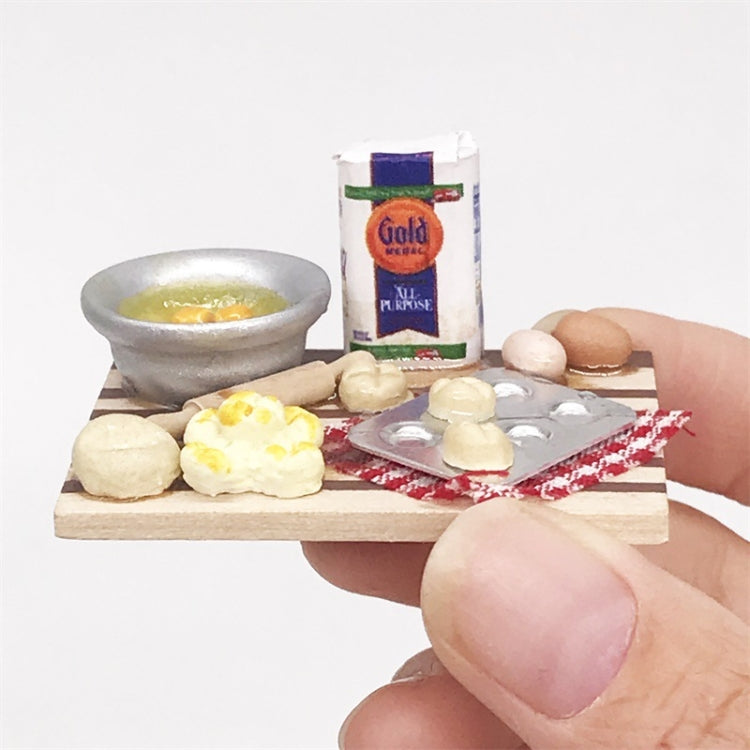 Mini chopping board held by hand, with toy bread, eggs, and metal blister tray