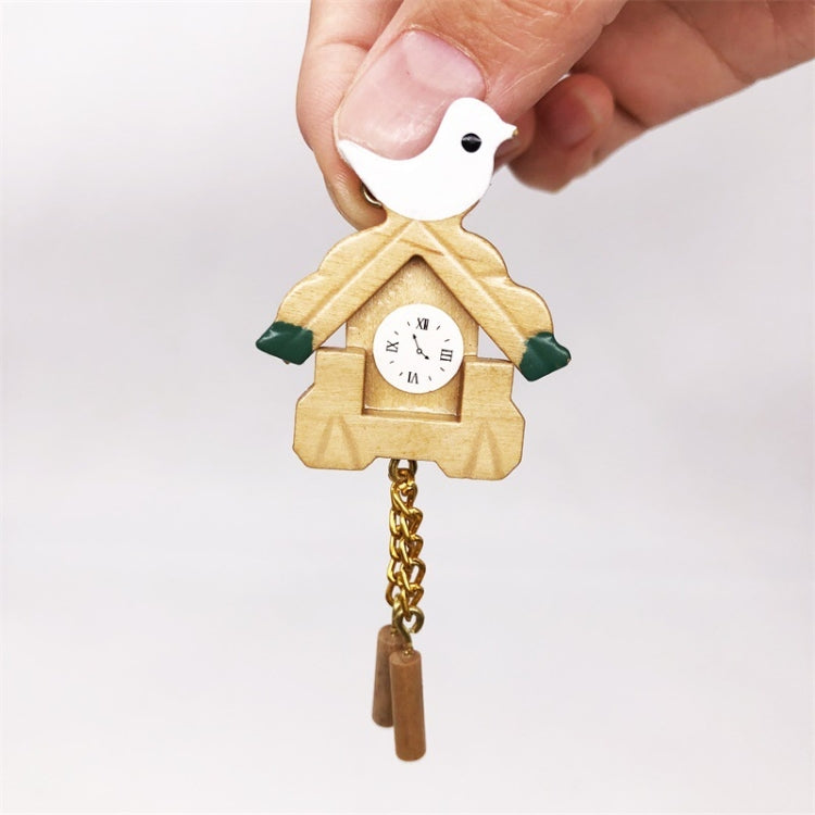 Mini wooden birdhouse clock held in hand; white bird top, round face, gold chain weights