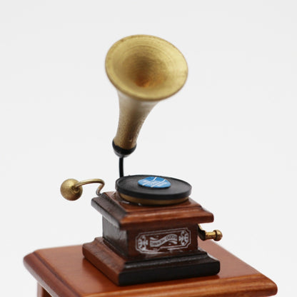 Mini retro gramophone toy with brass horn and black record on wooden base