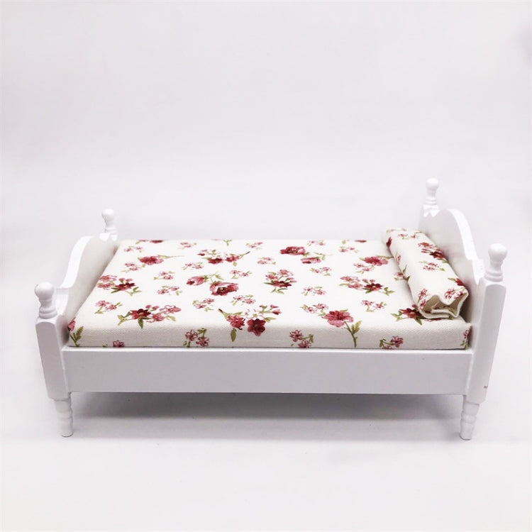 Miniature white single bed with floral mattress and pillow, front view