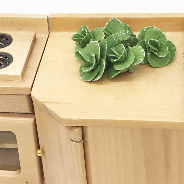Mini faux cabbage toy pieces on miniature wooden shelf, green curled leaves