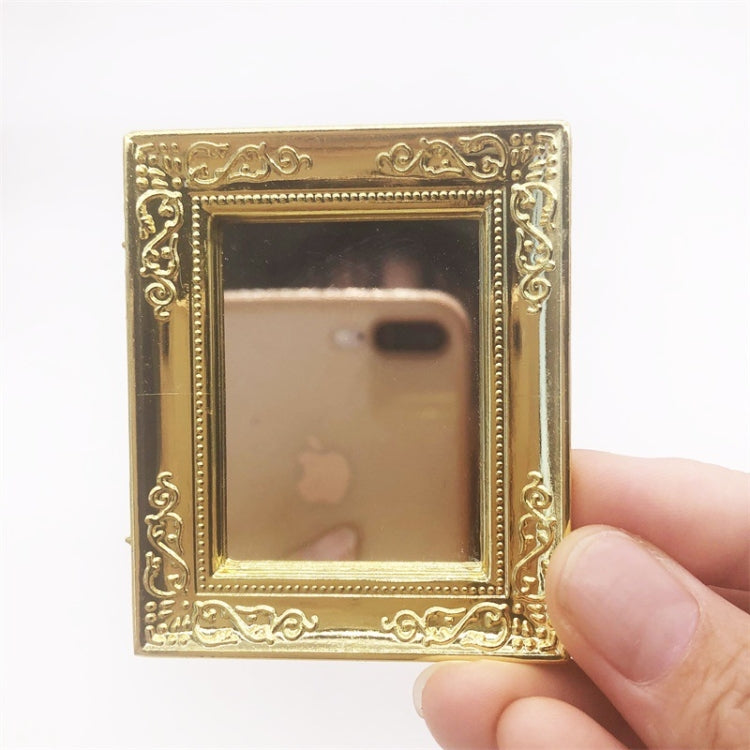 Mini wall mirror toy held up, gold filigree square frame with reflective glass