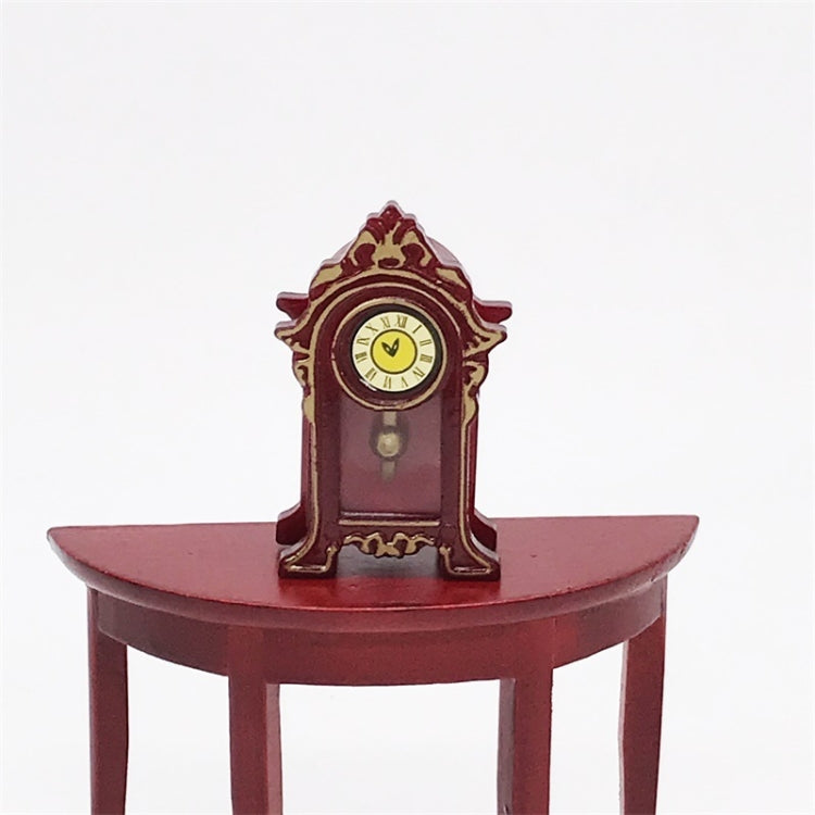 Mini vintage toy clock on red round tabletop, yellow face with Roman numerals and pendulum knob