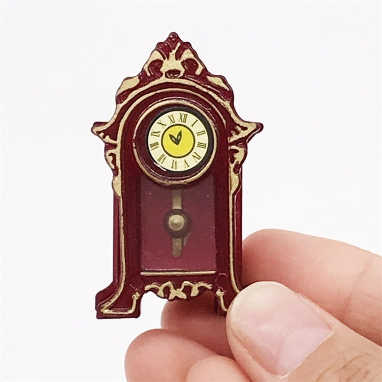 Mini vintage toy clock close-up held in hand, burgundy body, gold trim, yellow clock face